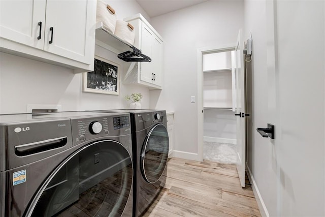 laundry room with light wood-style floors, baseboards, cabinet space, and washing machine and dryer