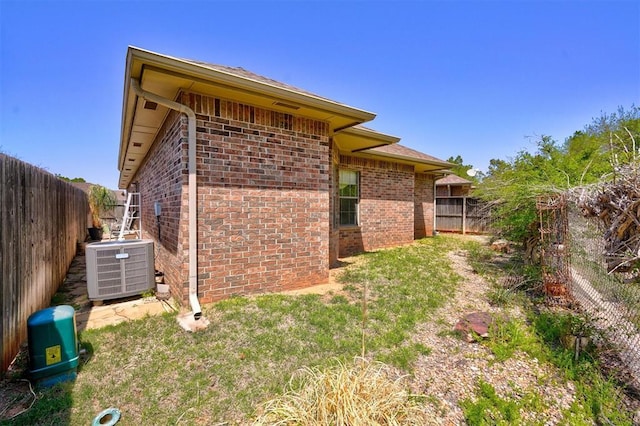 4408 32nd Pl, Oklahoma City, OK 73112 - view of side of home with central AC unit, a fenced backyard, and brick siding