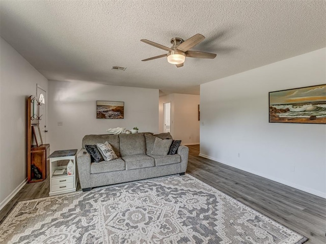 living room featuring a textured ceiling, wood finished floors, a ceiling fan, and visible vents