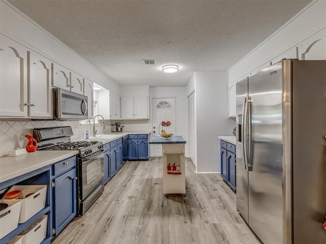 kitchen featuring light wood-style flooring, backsplash, visible vents, stainless steel appliances, and blue cabinets