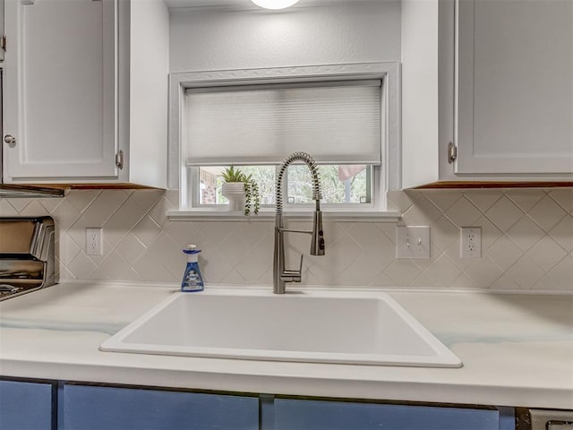 kitchen featuring white cabinets, tasteful backsplash, light countertops, and a sink