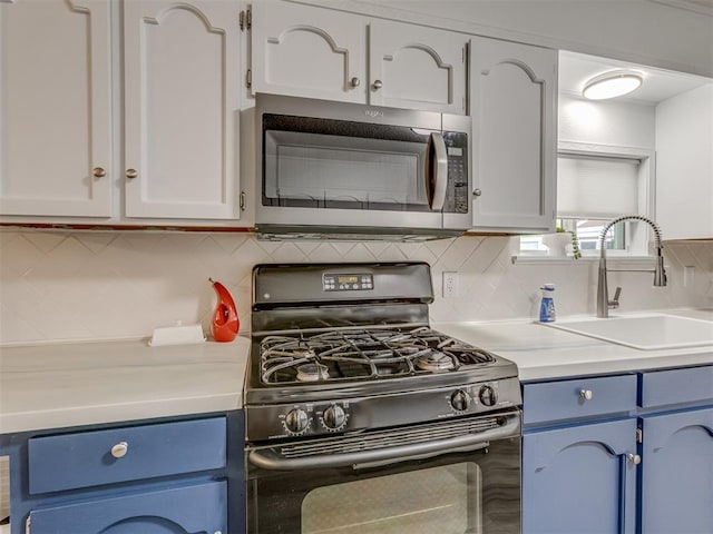 kitchen with black range with gas cooktop, blue cabinets, stainless steel microwave, light countertops, and a sink