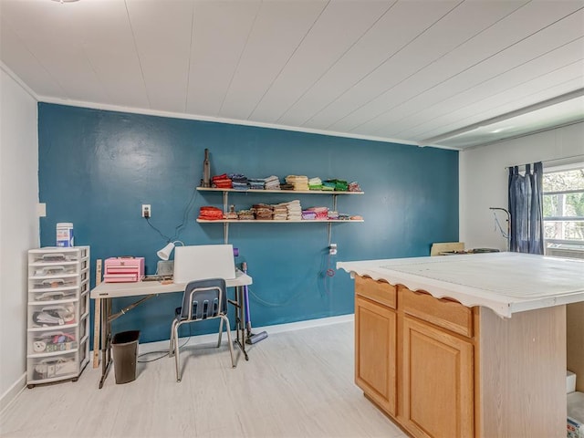 kitchen with baseboards, ornamental molding, light countertops, light wood-style floors, and light brown cabinetry