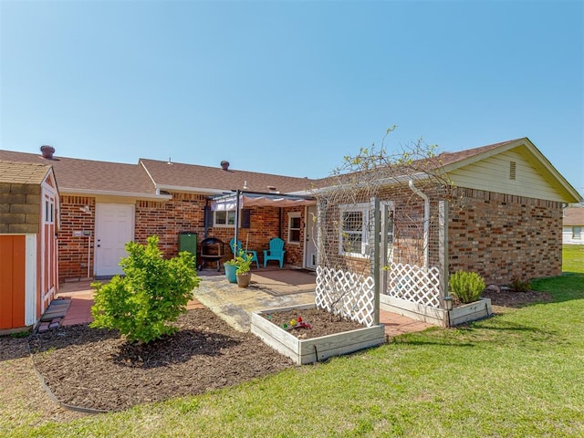 back of property featuring brick siding, a garden, a lawn, and a patio area