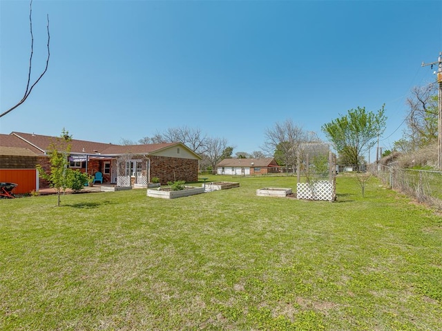 view of yard with a patio area, a fenced backyard, and a vegetable garden