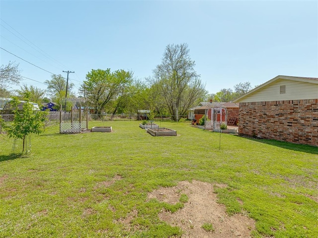 view of yard featuring an outdoor structure, fence, and a vegetable garden
