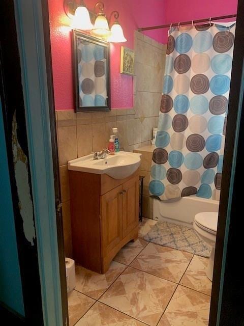 4115 S Shields Blvd, Oklahoma City, OK 73129 - full bath with tile patterned floors, vanity, shower / bathtub combination with curtain, tile walls, and toilet
