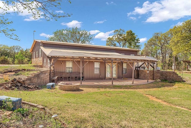 rear view of property with a patio, a yard, and a fire pit