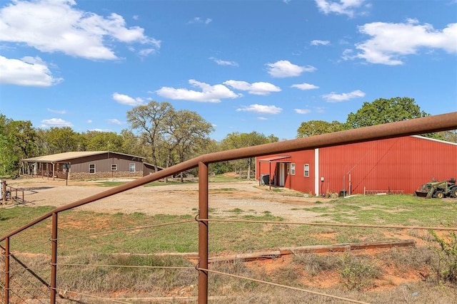 view of yard featuring fence, a pole building, and an outdoor structure