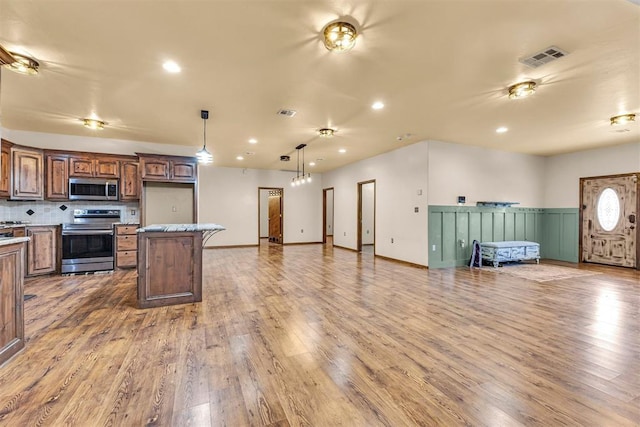 kitchen with visible vents, a center island, open floor plan, appliances with stainless steel finishes, and light wood-style flooring