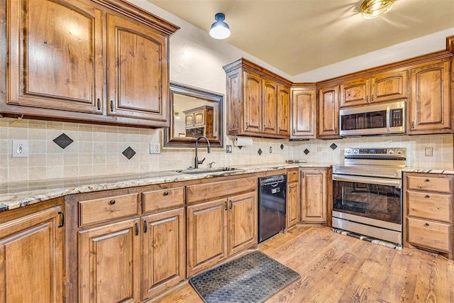 kitchen with a sink, stainless steel appliances, light wood finished floors, brown cabinets, and decorative backsplash