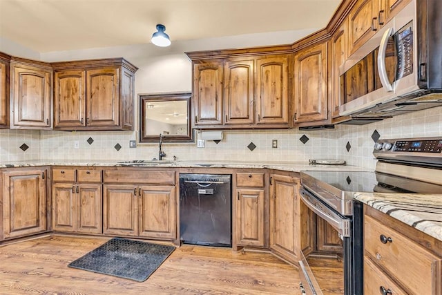 kitchen featuring decorative backsplash, a sink, light stone countertops, and stainless steel appliances