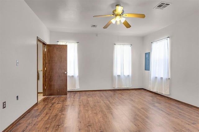 unfurnished room with visible vents, a ceiling fan, wood finished floors, and electric panel