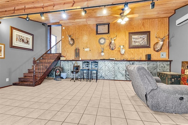 living area with track lighting, a wall mounted air conditioner, wood walls, ceiling fan, and wood ceiling