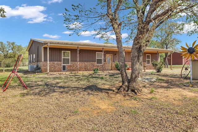 ranch-style house with central AC unit, stone siding, and board and batten siding
