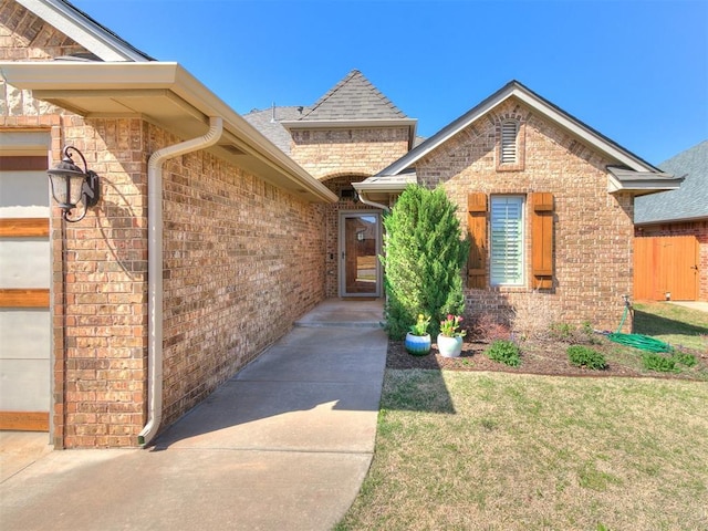 13340 Greenscape Rd, Piedmont, OK 73078 - view of exterior entry with an attached garage, a lawn, and brick siding