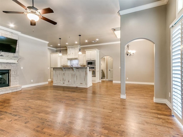 13340 Greenscape Rd, Piedmont, OK 73078 - unfurnished living room with a healthy amount of sunlight, ceiling fan, arched walkways, and a fireplace