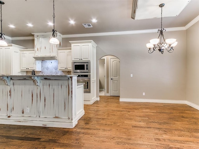 13340 Greenscape Rd, Piedmont, OK 73078 - kitchen featuring visible vents, arched walkways, ornamental molding, a breakfast bar, and stainless steel appliances