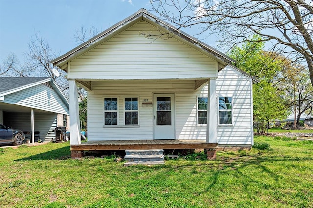 rear view of house with a yard, a porch, and a carport