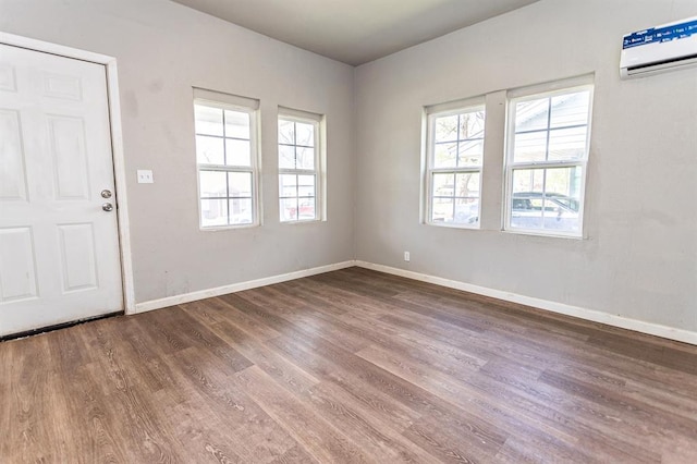 interior space featuring wood finished floors, a wall mounted air conditioner, and baseboards