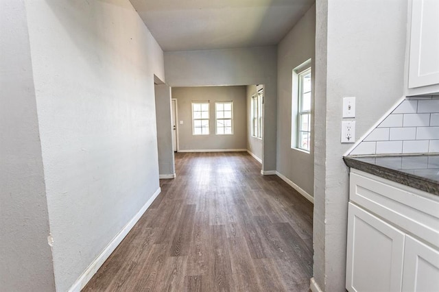 hallway with dark wood-type flooring and baseboards