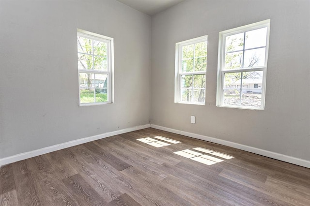 spare room with baseboards and wood finished floors
