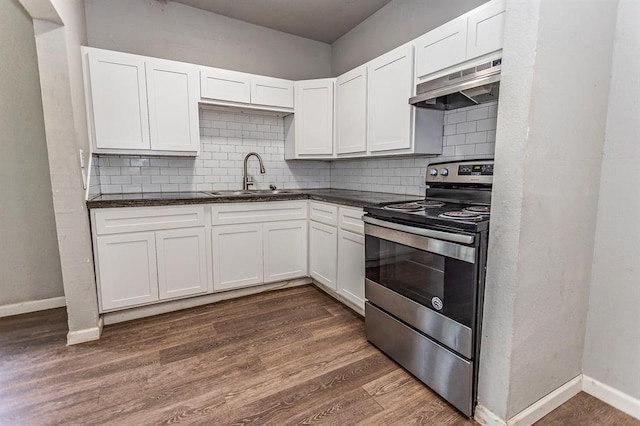 kitchen with baseboards, a sink, dark countertops, under cabinet range hood, and stainless steel electric range