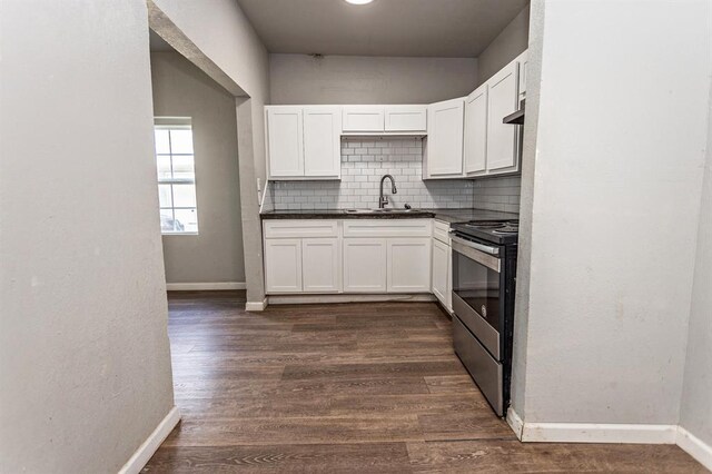 kitchen with tasteful backsplash, stainless steel range with electric cooktop, a sink, and baseboards