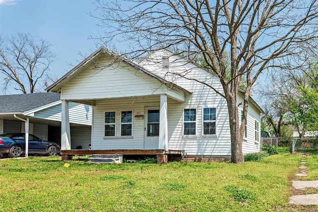 view of front facade featuring a front yard, fence, and an attached carport