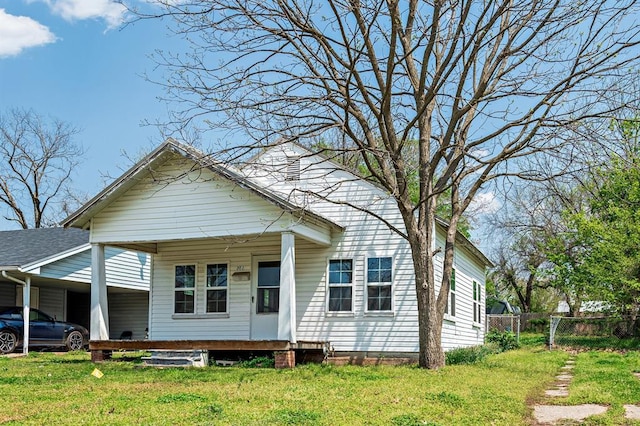 view of front facade featuring a carport, fence, and a front lawn