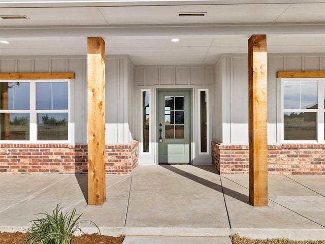 entrance to property with brick siding, visible vents, and board and batten siding