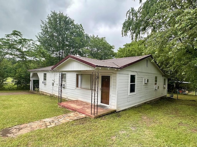 view of front facade with metal roof, cooling unit, and a front lawn