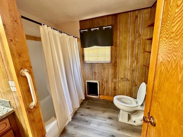 full bath featuring wooden walls, toilet, curtained shower, and wood finished floors