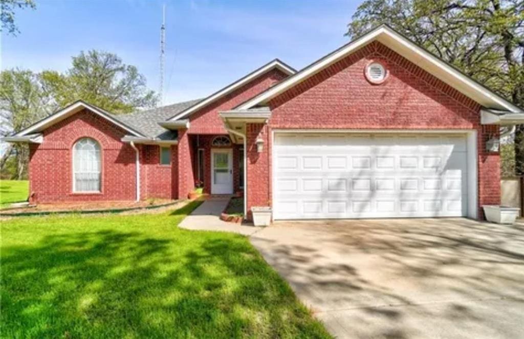 20991 NE 63rd St, Harrah, OK 73045 - single story home featuring an attached garage, concrete driveway, a front yard, and brick siding