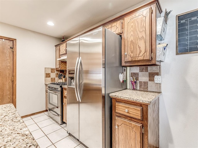 933 Luglena Ln, Purcell, OK 73080 - kitchen with stainless steel appliances, backsplash, light countertops, under cabinet range hood, and light tile patterned floors