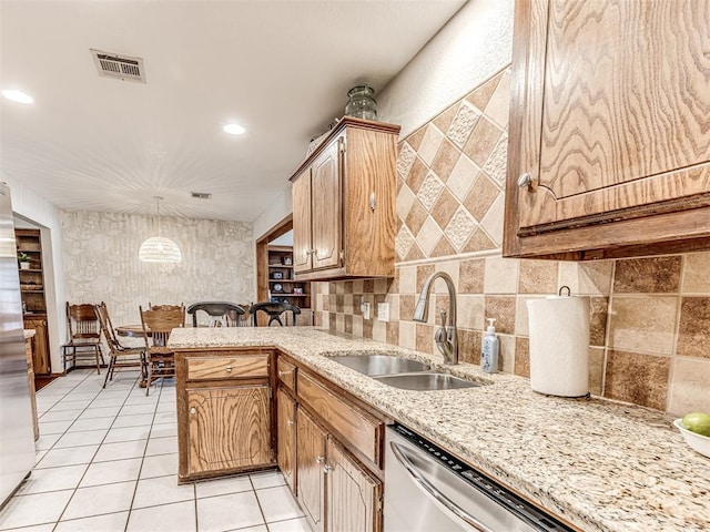 933 Luglena Ln, Purcell, OK 73080 - kitchen with a sink, light tile patterned floors, light stone counters, stainless steel dishwasher, and decorative light fixtures