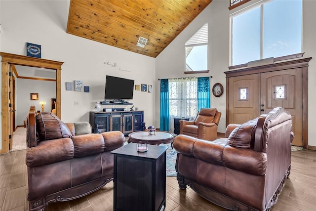 living area with high vaulted ceiling, visible vents, and wood finished floors
