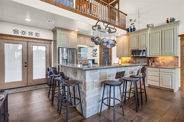 kitchen with a center island with sink, dark wood finished floors, visible vents, and stainless steel appliances