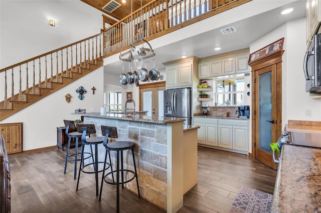kitchen with stainless steel fridge, plenty of natural light, a high ceiling, cream cabinets, and visible vents