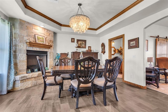 dining space with a raised ceiling, wood finished floors, a notable chandelier, and ornamental molding