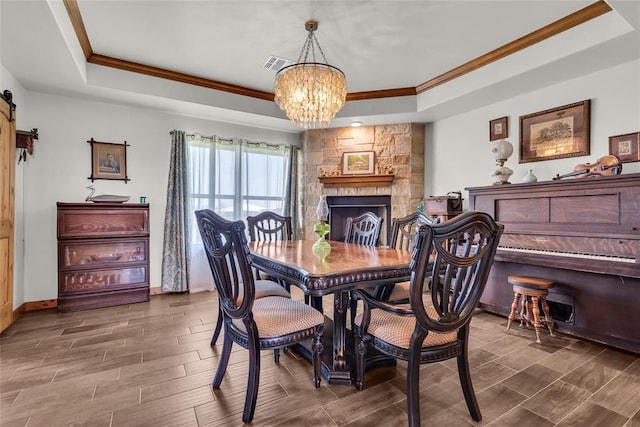 dining room with an inviting chandelier, ornamental molding, visible vents, a raised ceiling, and wood finished floors