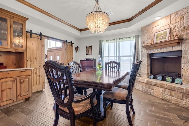 dining space featuring plenty of natural light, a barn door, crown molding, and a raised ceiling
