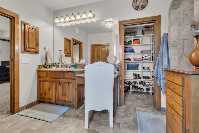 bathroom featuring a walk in closet and vanity