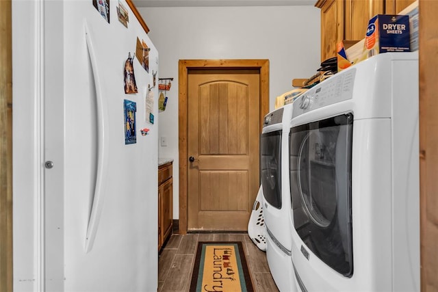 washroom featuring cabinet space, washing machine and dryer, and dark wood-style floors