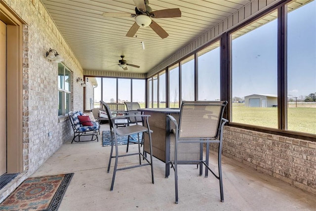 sunroom with outdoor dining area and a ceiling fan