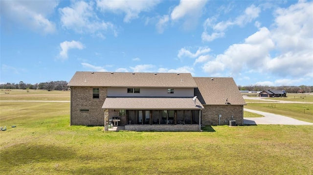 back of property featuring a yard, roof with shingles, cooling unit, and a sunroom