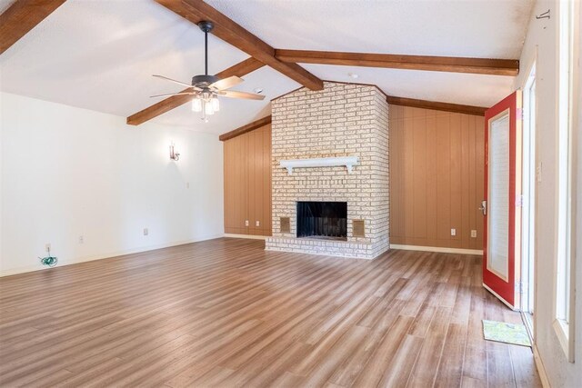 515 W Tennessee Ave, Pauls Valley, OK 73075 - unfurnished living room featuring light wood finished floors, ceiling fan, a fireplace, wooden walls, and baseboards