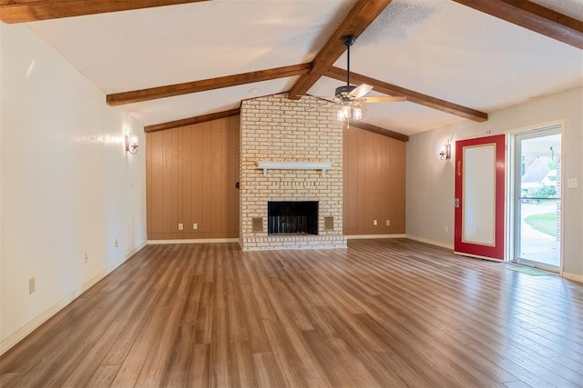 515 W Tennessee Ave, Pauls Valley, OK 73075 - unfurnished living room featuring wood finished floors, a ceiling fan, a brick fireplace, baseboards, and wooden walls