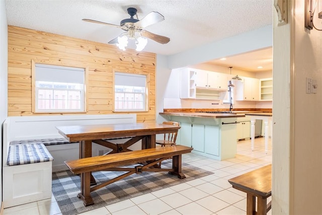 515 W Tennessee Ave, Pauls Valley, OK 73075 - dining space featuring wooden walls, a textured ceiling, a ceiling fan, and light tile patterned floors