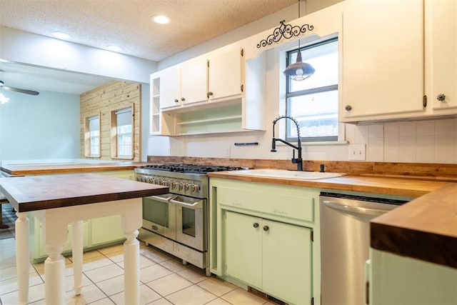 515 W Tennessee Ave, Pauls Valley, OK 73075 - kitchen featuring appliances with stainless steel finishes, a textured ceiling, a sink, wooden counters, and backsplash